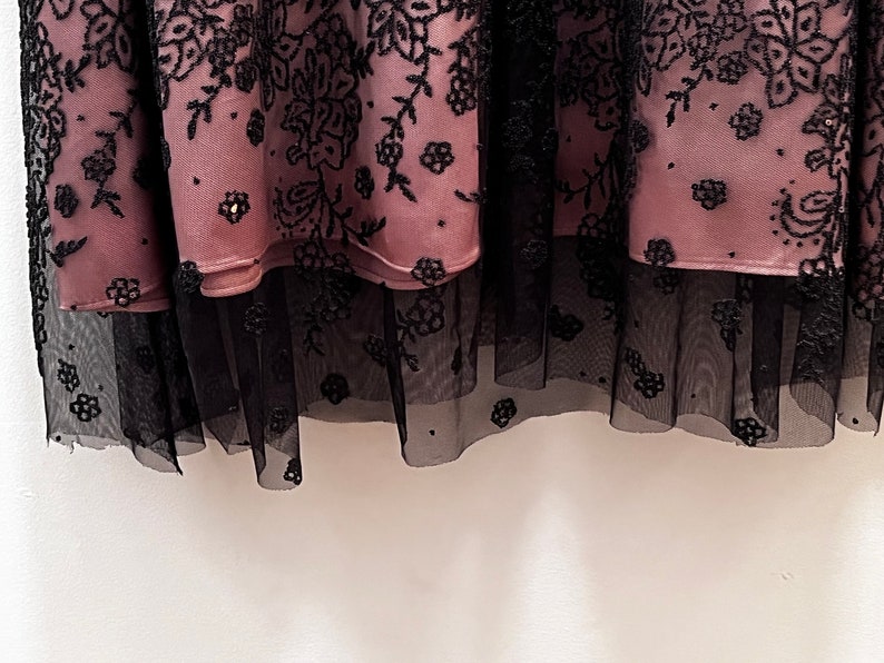 May include: A pink skirt with black floral embroidery and a black tulle underskirt.