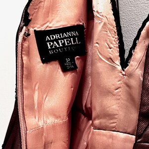 May include: A black and pink dress with a black lace trim. The dress has a label that reads "Adrianna Papell Boutique" and "Size 8 Made in China".