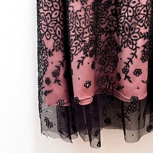 May include: A pink and black lace skirt with a floral pattern. The skirt has a layer of black tulle underneath.