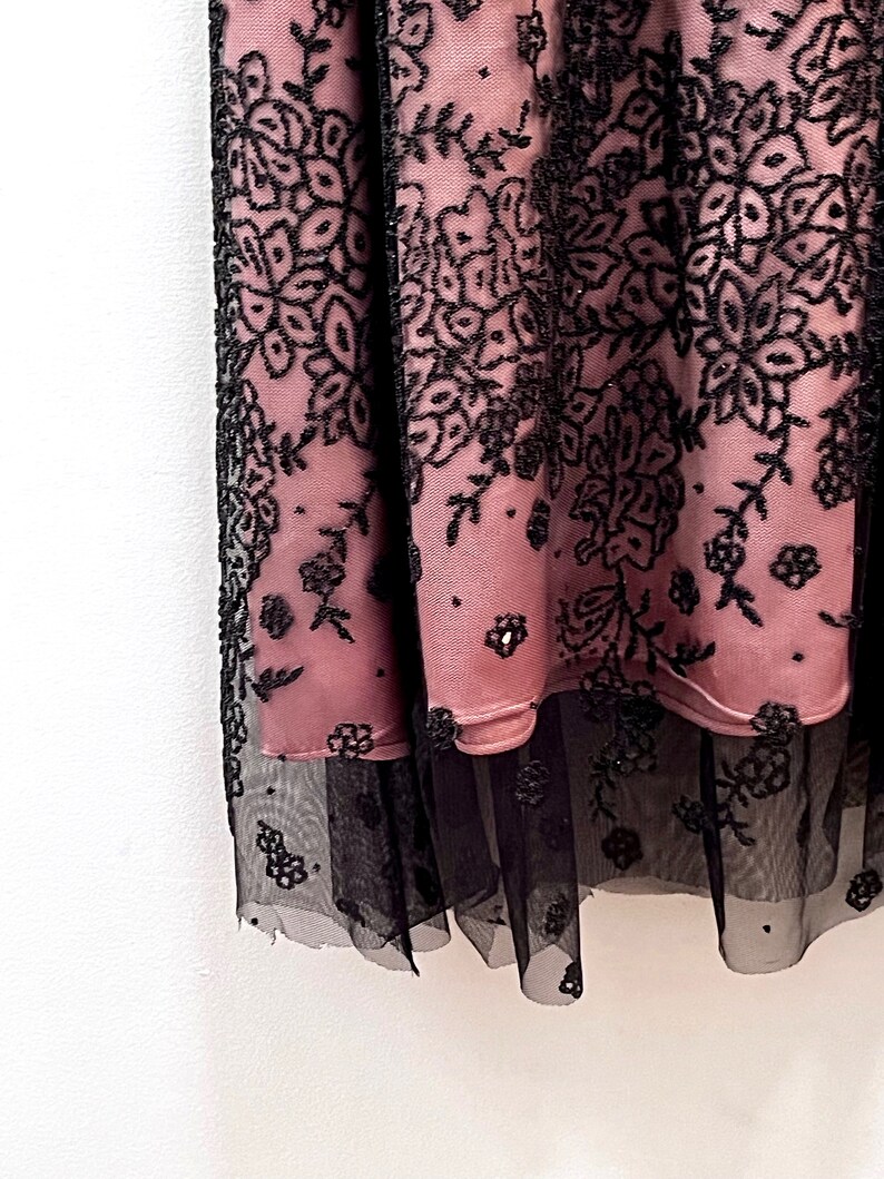 May include: A pink and black lace skirt with a floral pattern. The skirt has a layer of black tulle underneath.