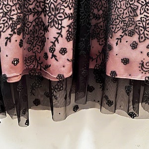 May include: A pink skirt with black floral embroidery and a black tulle overlay.