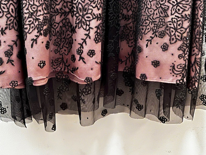 May include: A pink skirt with black floral embroidery and a black tulle overlay.