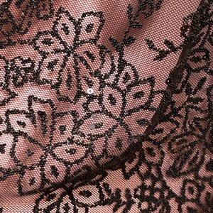 May include: Close-up of black lace fabric with a floral pattern and small sequins. The fabric is sheer and has a delicate texture.