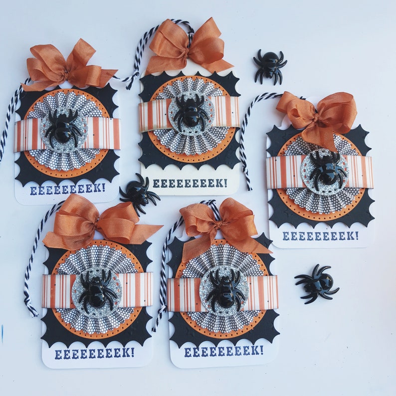 May include: Five Halloween-themed gift tags with orange and black striped paper, black and white patterned paper, and black spiders. The tags are decorated with orange and black ribbon bows and have the text "EEEEEEEEK!" printed on them.