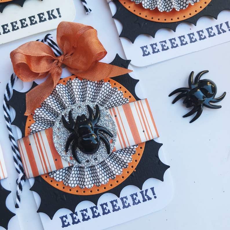 May include: A black and orange Halloween card with a spider web design and the text "EEEEEEK!" repeated three times. A black spider with silver glitter is attached to the card.