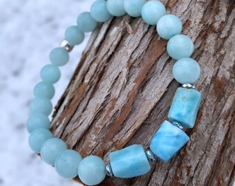 Puede incluir: Un brazalete de piedras preciosas azul claro con detalles plateados. El brazalete presenta cuentas redondas y cuentas rectangulares más grandes.