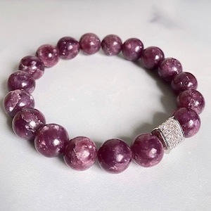 Peut inclure: Un bracelet en pierres précieuses violettes avec un fermoir argenté. Le bracelet est composé de perles rondes et comporte un accent argenté scintillant.