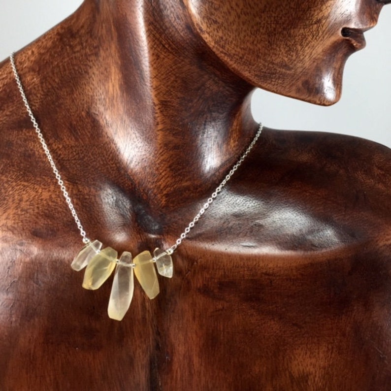 May include: A silver chain necklace with a cluster of six light yellow, faceted, teardrop-shaped stones.