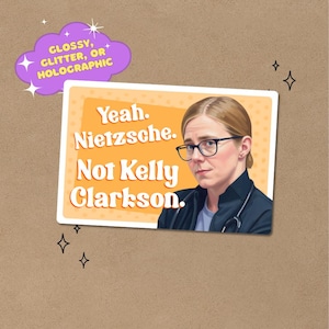May include: A sticker featuring a woman in glasses and a medical coat, with the text "Yeah. Nietzsche. Not Kelly Clarkson." A purple cloud graphic in the upper left corner reads "Glossy, Glitter, or Holographic". The background is a tan color.