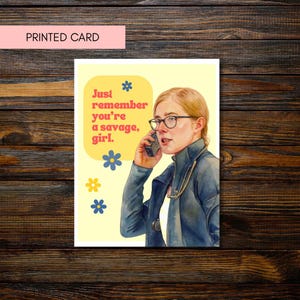 May include: Printed card with a watercolor illustration of a person wearing glasses and a blue jacket, holding a phone. The card has the text "Just remember you're a savage, girl." and decorative flowers.