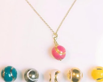 Padel ball necklace in silver with gold bath and ball in ceramic and gold/platinum. Fire, passion, colour, technique: the sport of the moment.