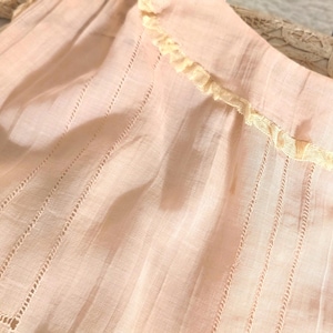 Vestido infantil rosa de voile transparente de los años 20 con cuello de encaje bordado, sin mangas y estilo veraniego.