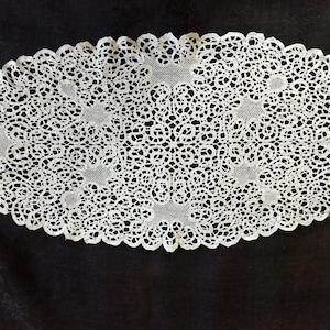 May include: White crocheted oval doily with a delicate floral pattern.