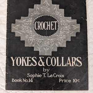 May include: Vintage crochet pattern book titled "OLD & NEW DESIGNS In CROCHET YOKES & COLLARS" by Sophie T. La Croix. The cover is black with white text and a detailed crochet design. Book No. 14.