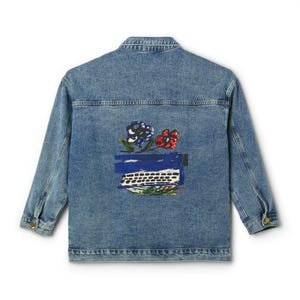 May include: A light blue denim jacket with a button-down front and long sleeves. The back of the jacket features a colorful embroidered design of a typewriter, flowers, and foliage. The jacket is a classic style.