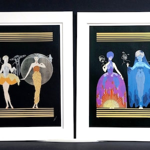 May include: Two framed prints of art deco style illustrations featuring women in elaborate gowns and hats. The prints are set against a black background with gold accents.