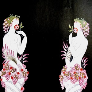 Op de afbeelding: Twee figuren met witte lichamen en bloemendecoraties staan tegen een zwarte achtergrond. Beide figuren zijn versierd met roze en rode bloemen, en ze houden allebei een enkele rode bloem in hun mond.