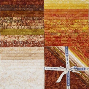 May include: A collection of fabric strips featuring batik patterns in shades of brown, tan, cream, yellow, orange, and red. The strips are arranged in stacks and a bundled square set tied with a white ribbon printed with the text ISLAND BATIK.