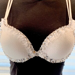 May include: White bra with a ruffled trim and rhinestones.