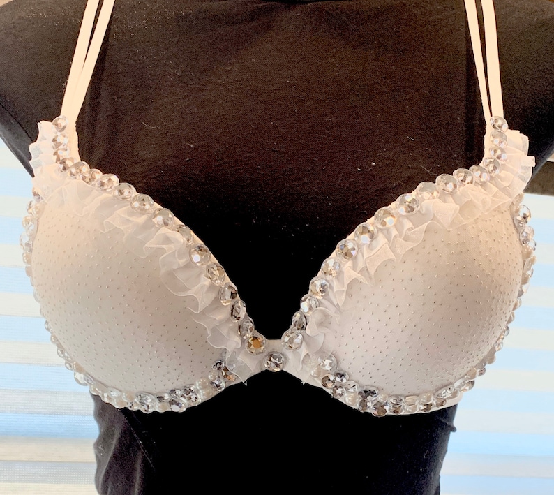 May include: White bra with a ruffled trim and rhinestones.