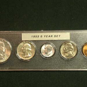 May include: A 1953 S Year Set of US coins displayed in a clear plastic holder. The set includes a silver half dollar, a quarter, a dime, a nickel, and a copper penny. The coins are in good condition.