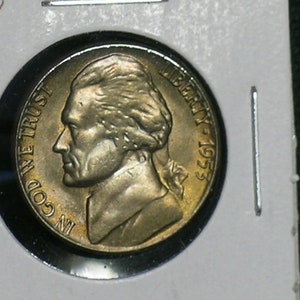 May include: A silver US half dollar coin with the profile of Thomas Jefferson on the obverse. The coin has the inscription "IN GOD WE TRUST" and "LIBERTY 1953".