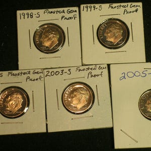 May include: Five proof coins in protective holders. The coins are dimes, with the profile of a man on the obverse. The holders are labeled with the years 1998, 1999, 2002, 2003, and 2005, and the words "Frosted Gem Proof".