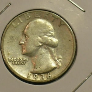 May include: A silver 1936 quarter coin. The coin features a profile of a person on the obverse, with the word "LIBERTY" above and "IN GOD WE TRUST" below. The year "1936" is visible.