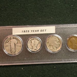 May include: A 1925 Year Set of U.S. coins displayed in a clear plastic holder. The set includes a Standing Liberty quarter, a Mercury dime, a Buffalo nickel, and a Lincoln penny. The coins are silver and copper in color.