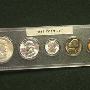 May include: A 1953 Year Set of U.S. coins displayed in a clear plastic holder. The set includes a silver half dollar, quarter, dime, nickel, and a copper penny. The coins are in good condition, with visible details of the historical figures.