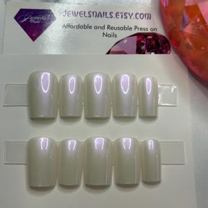 Puede incluir: Un conjunto de uñas postizas nacaradas de forma cuadrada, dispuestas en dos filas de cinco. Las uñas tienen un brillo sutil y están montadas en una tarjeta blanca. El texto "JEWELSNALS.ETSY.com Affordable and Reusable Press on Nails" es visible.