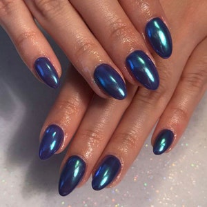 May include: Close-up of hands with oval-shaped nails painted in a dark blue iridescent nail polish.