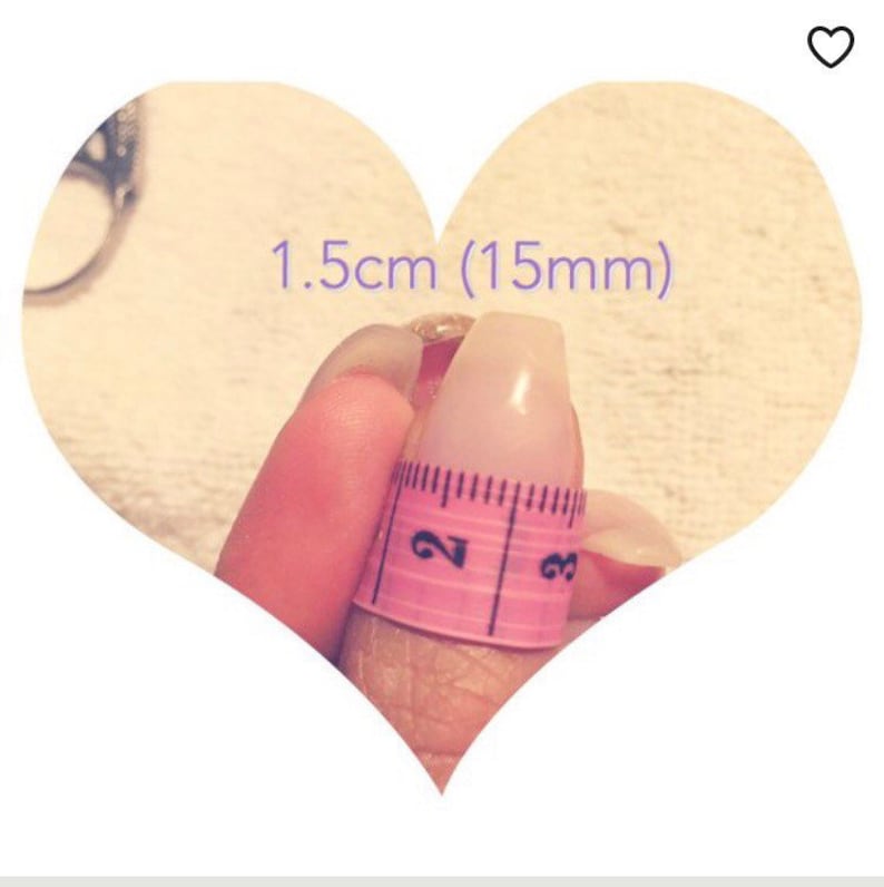 Puede incluir: Una cinta m&eacute;trica rosa envuelta alrededor de un dedo, mostrando una medida de 1,5 cm (15 mm).
