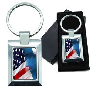May include: A silver key chain with a rectangular frame featuring a close-up image of the American and Finnish flags waving together. The key chain is packaged in a black gift box.