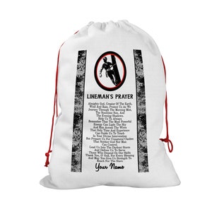 May include: White drawstring bag featuring a lineman graphic within a circular frame. The bag displays the "Lineman's Prayer" text in black, with red drawstrings. The design includes a space for a personalized name.