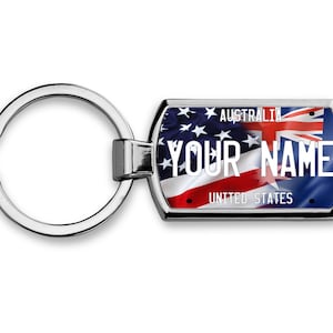 May include: A silver key chain with a rectangular tag featuring the American and Australian flags. The tag says "Australia" and "United States" at the top and bottom, with "YOUR NAME" in the center.
