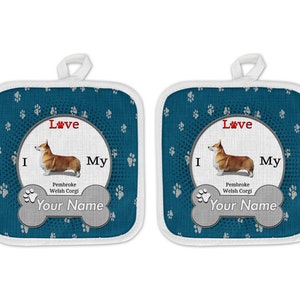 May include: A pair of blue and white pot holders with a paw print design. The pot holders feature a white oval with the text "I Love My Pembroke Welsh Corgi" and a space for a name. The pot holders are perfect for protecting your hands while cooking.