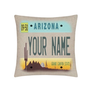 May include: A tan linen pillow with a printed design of an Arizona license plate. The license plate has the text "09-50", "ARIZONA", "YOUR NAME", and "GRAND CANYON STATE".