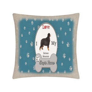 Op de afbeelding: Een blauw en wit kussen met een pootjespatroon. Het kussen heeft een witte ovaal met de tekst "Ik hou van mijn Berner Sennenhond-naam".