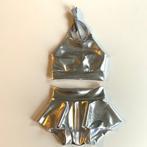 May include: A silver metallic two-piece dance outfit with a halter top and a ruffled skirt.