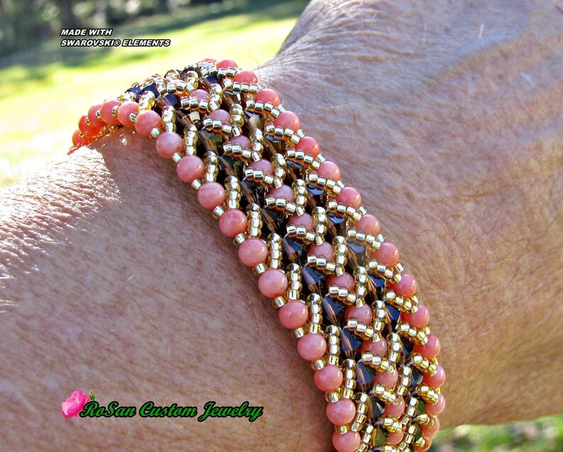 May include: A pink and gold beaded bracelet with a geometric pattern. The bracelet is made with Swarovski Elements and is labeled "RoSan Custom Jewelry".