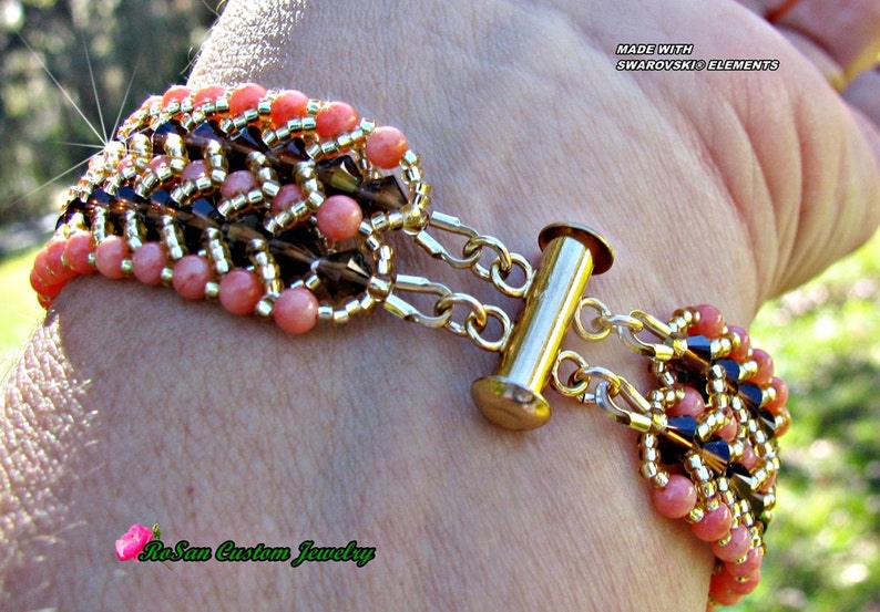 May include: A multi-strand bracelet with pink, gold, and black beads. The bracelet has a gold toggle clasp and is made with Swarovski elements. The bracelet is on a person's wrist. "RoSan Custom Jewelry" is written on the bracelet.