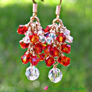 May include: Gold dangle earrings with red and clear crystal beads. The earrings are made with wire wrapped beads and have a teardrop shape.