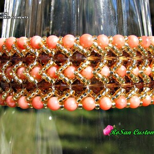 May include: A coral and gold beaded bracelet with a geometric pattern. The bracelet is made with Swarovski elements and is displayed on a glass surface. "RoSan Custom Jewelry" is written in the bottom right corner of the image.