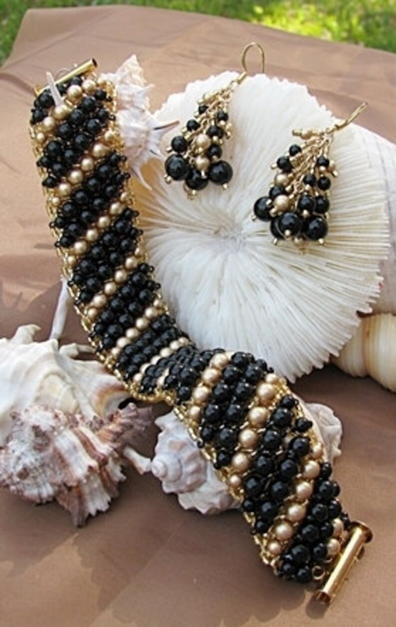 May include: A black and gold beaded bracelet and matching earrings. The bracelet is made with small black and gold beads woven together in a pattern. The earrings are dangle earrings with multiple tiers of black and gold beads.