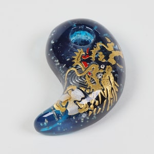 May include: A blue glass charm with a gold dragon design. The charm has a hole at the top for hanging.