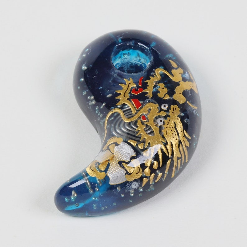 May include: A blue glass charm with a gold dragon design. The charm has a hole at the top for hanging.
