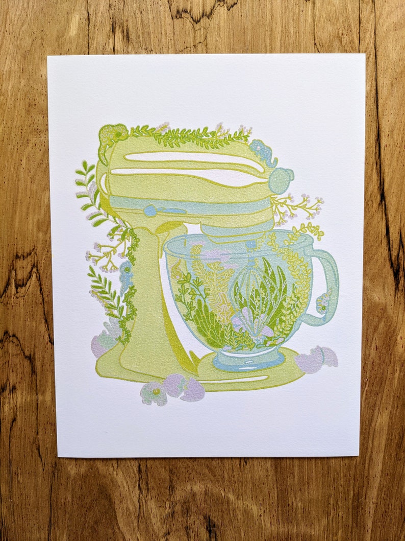 May include: A yellow and green kitchen mixer with a floral design. The bowl of the mixer is filled with green and white flowers.