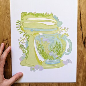 May include: A yellow stand mixer with a green floral design and a matching green floral teacup and saucer.
