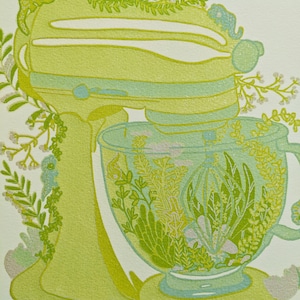 May include: A green stand mixer with a glass bowl filled with green and white floral designs. The mixer is decorated with green leaves and white flowers.